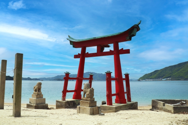 砂浜に立つ朱色の鳥居と、その向こうの海