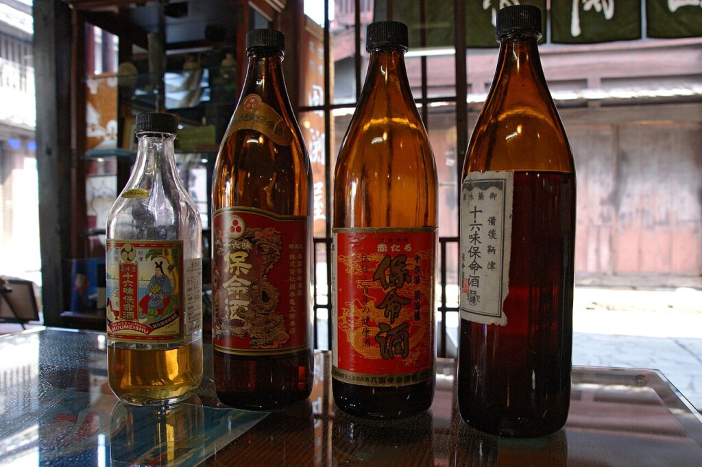 保命酒の瓶が並ぶ店先。琥珀色の酒と赤いラベル