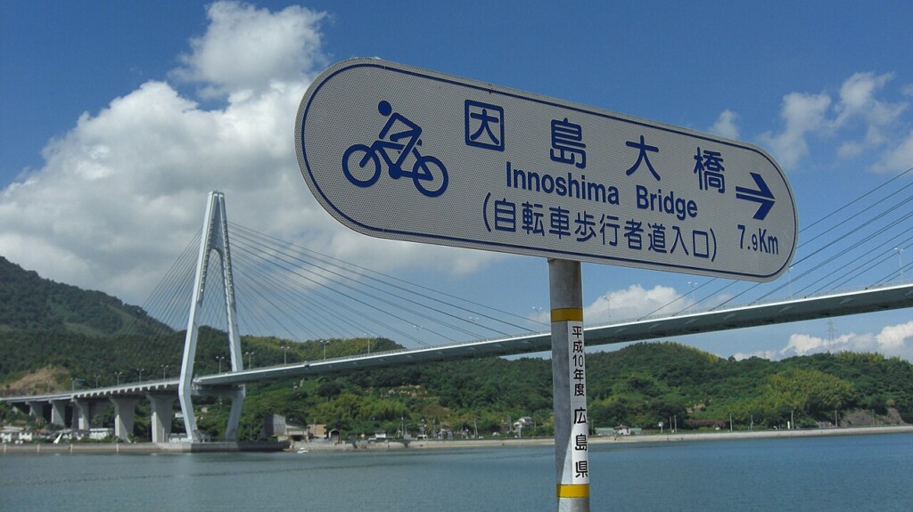 自転車歩行者道の案内標識と、その奥に架かるしまなみ海道の橋