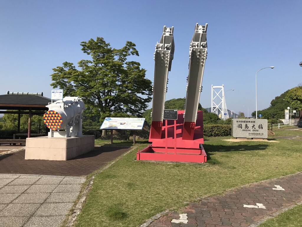 公園に置かれた大きなケーブルの模型と赤い支柱