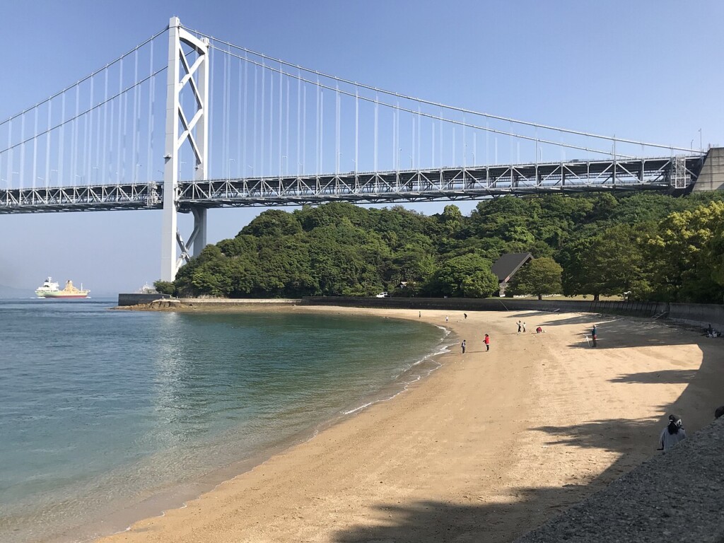 海沿いの砂浜と、奥に架かる因島大橋