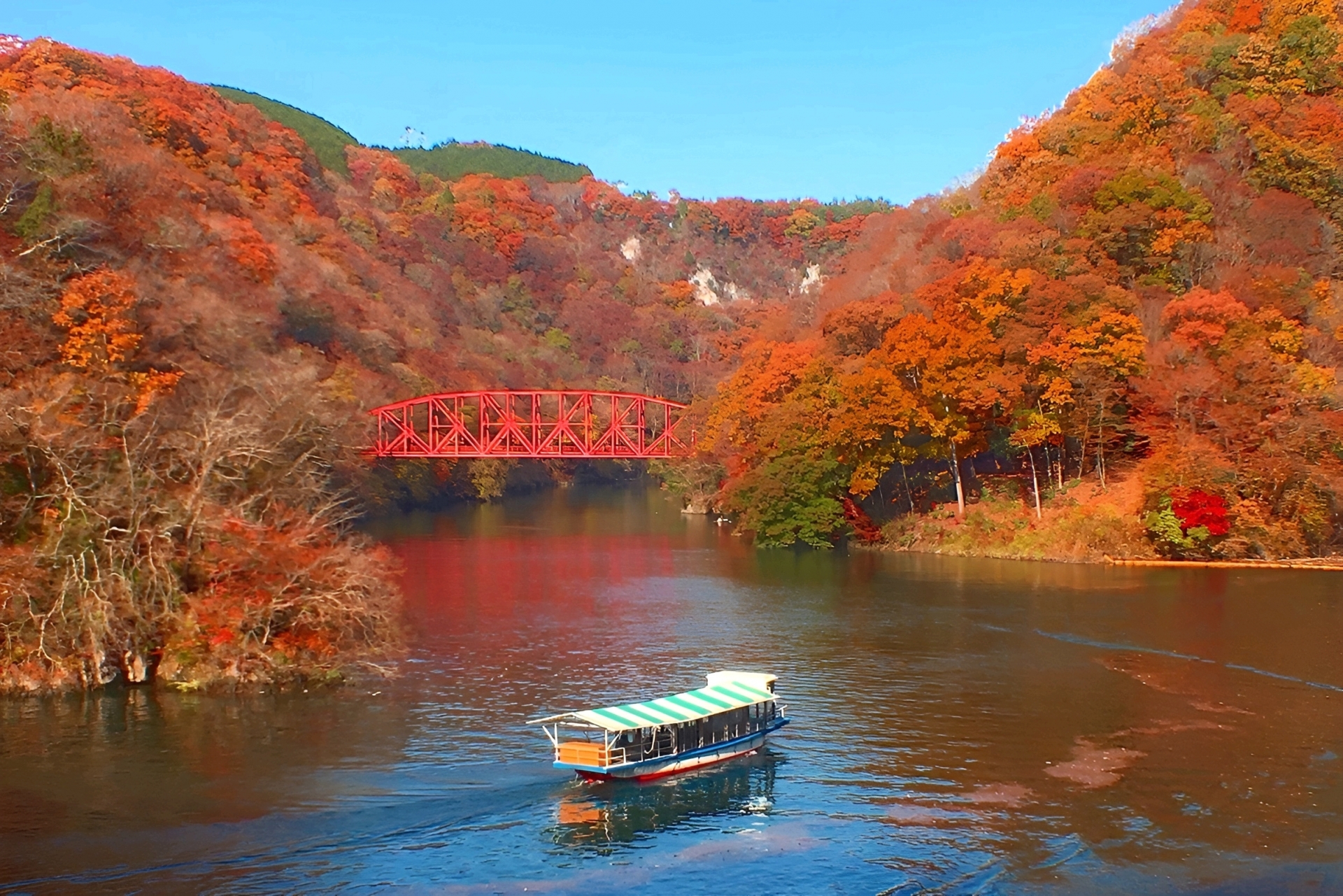 紅葉の神龍湖を進む遊覧船と赤い鉄橋