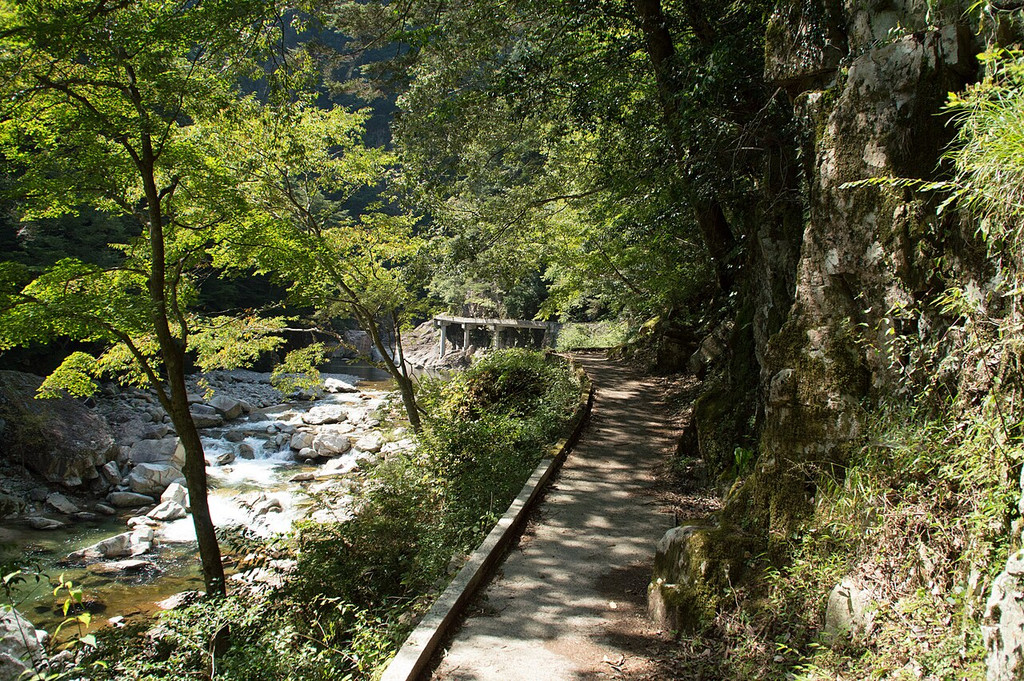 三段峡の渓谷沿いに続く舗装された遊歩道と切り立った岩壁